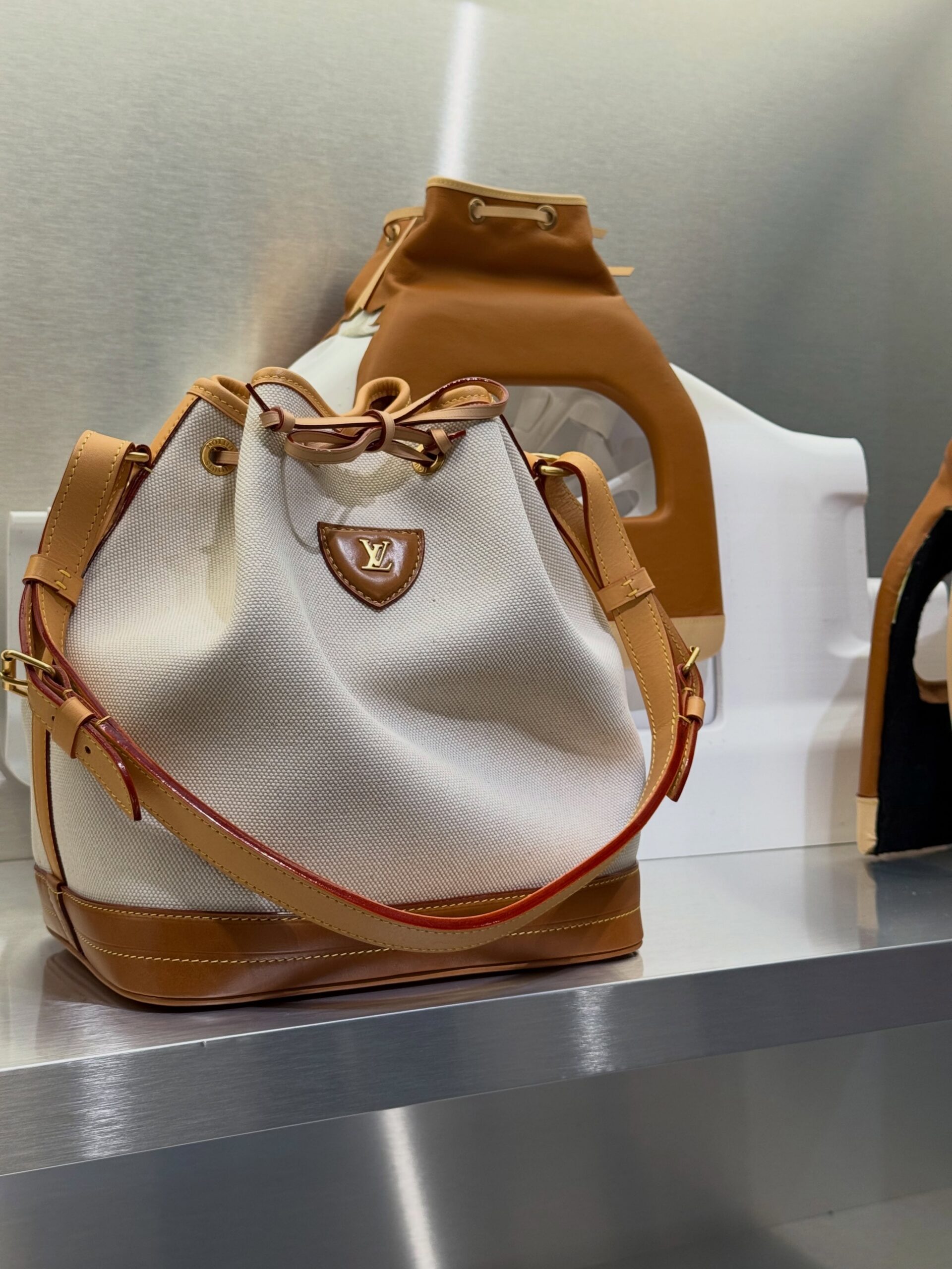 Cream canvas Louis Vuitton bucket bag with tan leather trim