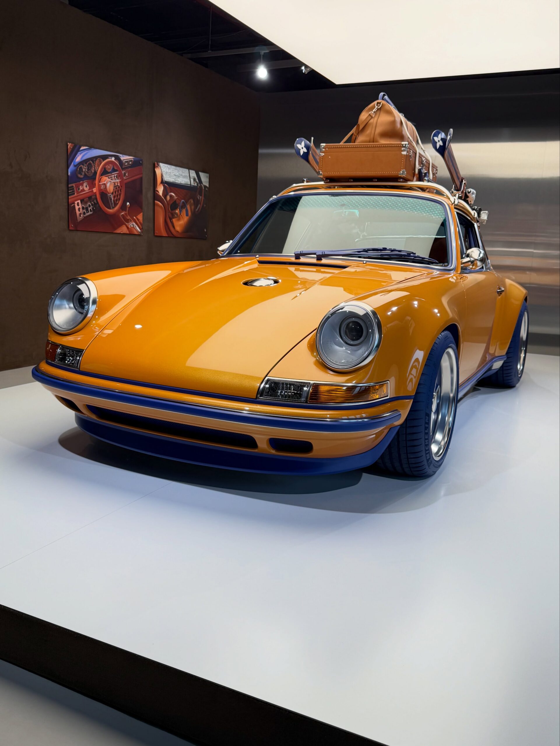 Orange 911 in the gallery space with LV luggage on the roof